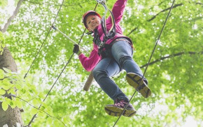 Child reaching platform climbing in high rope course